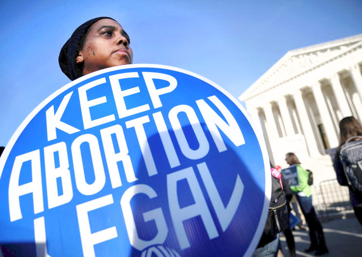 [Photo: A black, pro-choice protestor stands in front of the U.S. Supreme Court and holds a sign that reads 'Keep Abortion Legal.'