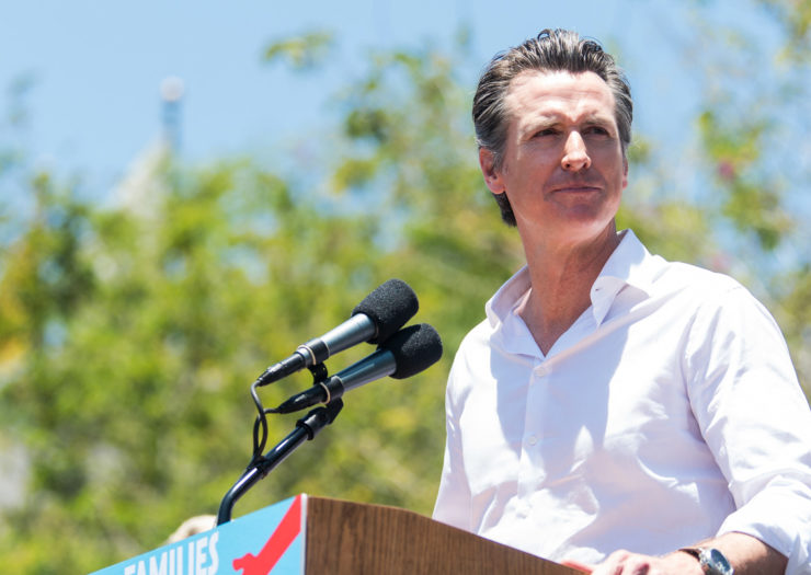 [Photo: Gov. Gavin Nesom delivers an outdoor speech at the Families Belong Together - Freedom for Immigrants march.]