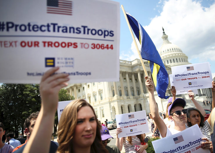[Photo: Various people rally outside of the Supreme Court, protesting the trans military ban.]