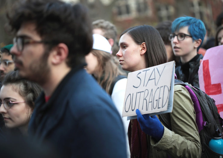 [Photo: Students hold signs as they gather for a rally on a college campus.]