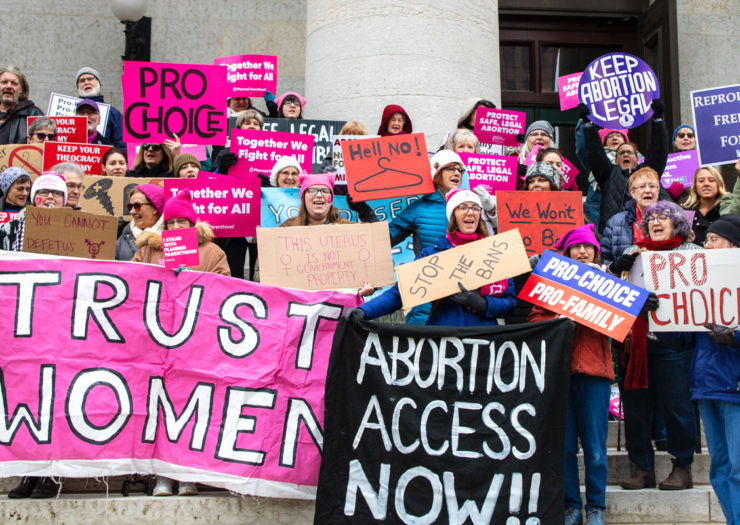[Photo: Pro-choice protesters hold up signs during a rally.]