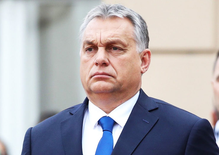 [Photo: Hungarian Prime Minister Viktor Orban looks stoic as he stands during an event.]