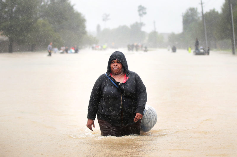 [Photo: A Black woman wades waist-deep in water during the aftermath of Hurricane Harvey.]