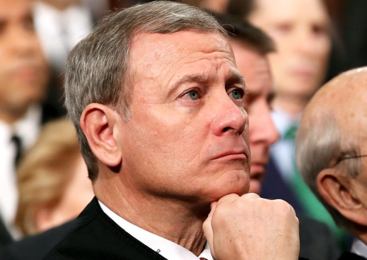 [Photo: United States Supreme Court Chief Justice John Roberts listens attentively to a speech.]