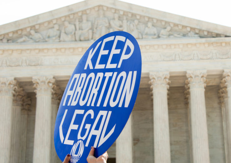 [Photo: A pro-choice activist holds a sign in front of the Supreme Court.]