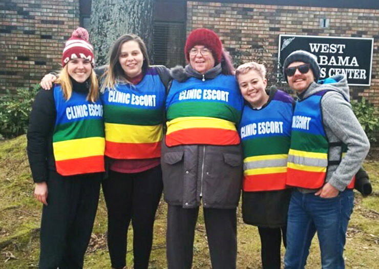 [Photo: Alabama Women's Center clinic escorts pose for a picture in front of the clinic.]
