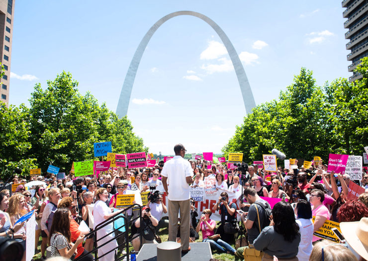[Photo: Protesters hold signs as they rally to protest Missouri's abortion ban.]