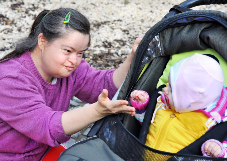 [Photo: A mother with Down syndrome plays with her toddler.]