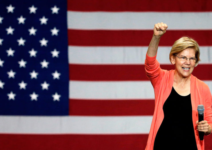 [Photo: Senator and Democratic Presidential hopeful Elizabeth Warren gestures with a power fist as she speaks during a town hall meeting.]