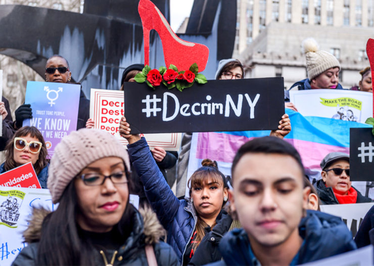 [Photo: A crowd of sexworker rights advocates gather holding signs that read '#decrimNY.'}