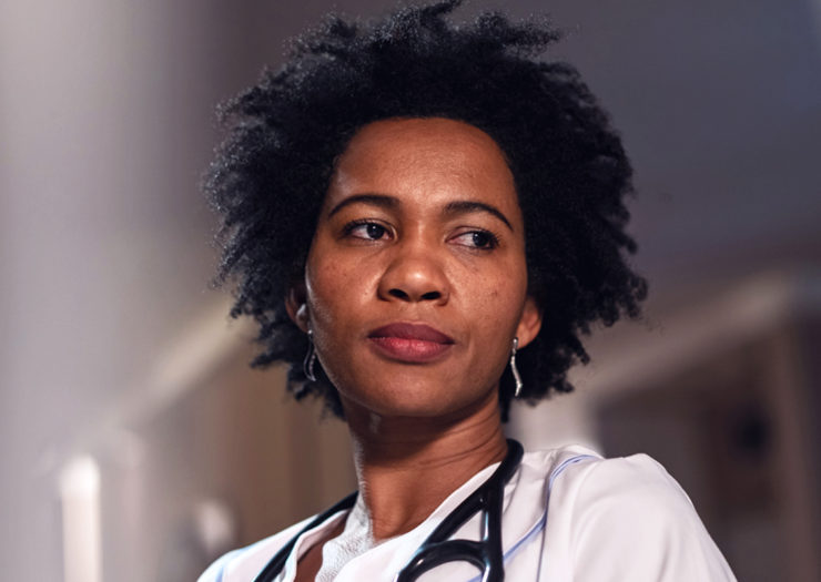 [Photo: A young, Black doctor looks pensive.]