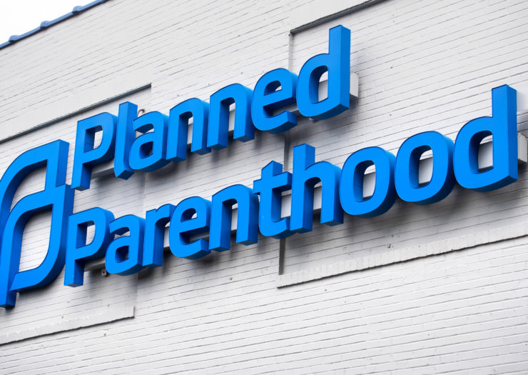 [Photo: A Planned Parenthood logo is pictured outside a Planned Parenthood building.]