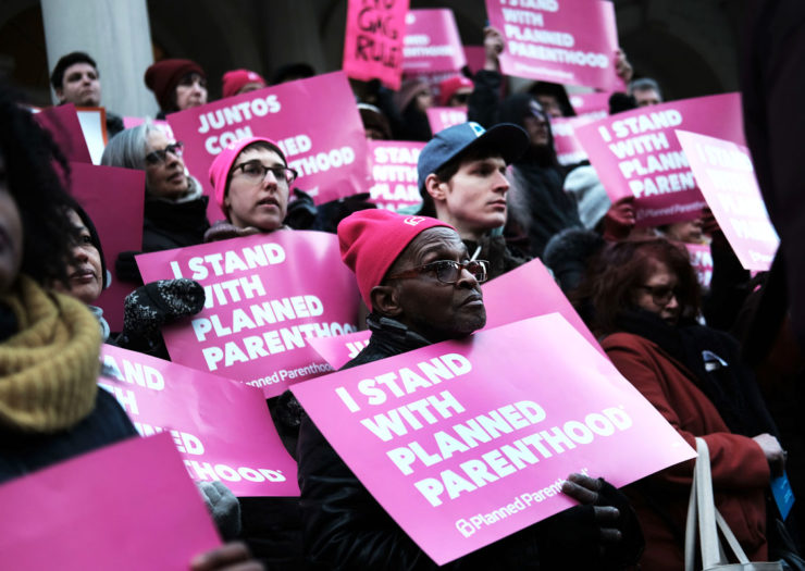 [Photo: Pro-choice supporters hold signs as they rally against the Global Gag Rule.]