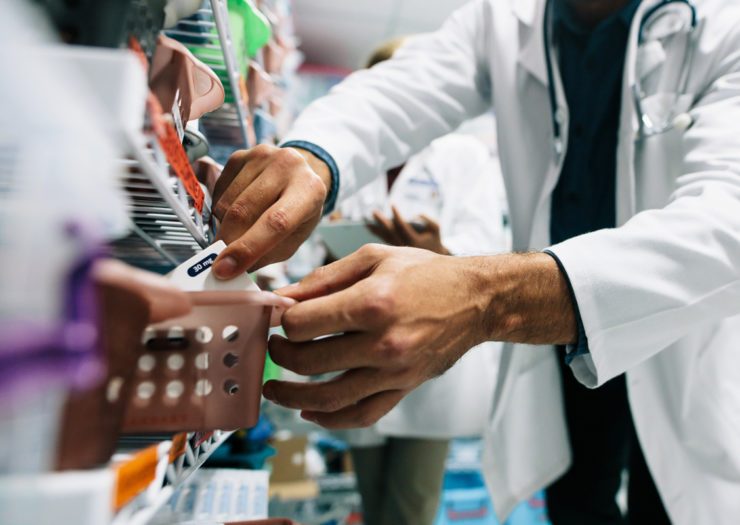 [Photo: A pharmacist looks for a prescription in a pharmacy.]
