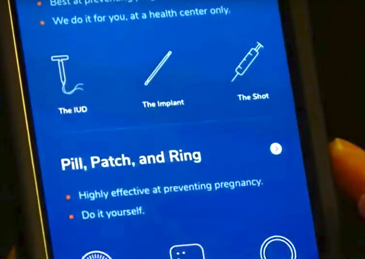 [Photo: A person holds a phone with an illuminated screen that shows different types of birth control.]