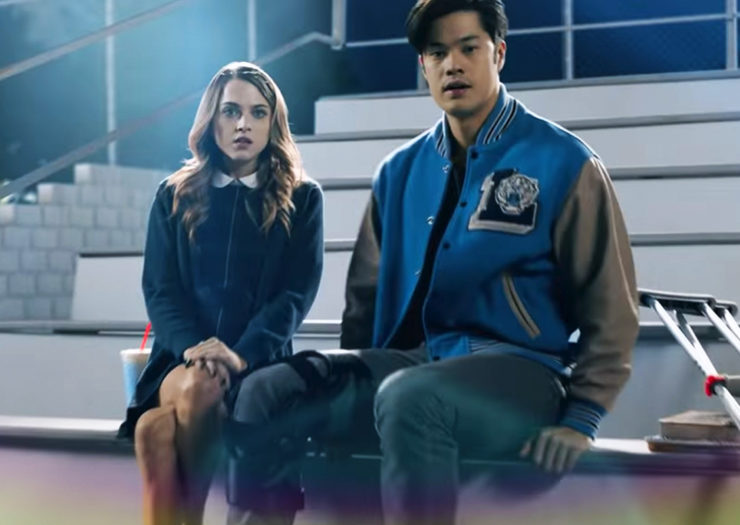 [Photo: Chloe and another character from 13 Reasons Why sit on school bleachers at night with surprised looks on their faces.]
