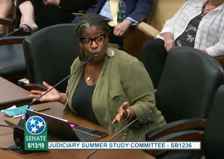 [Photo: Cherisse Scott speaks during a hearing.]
