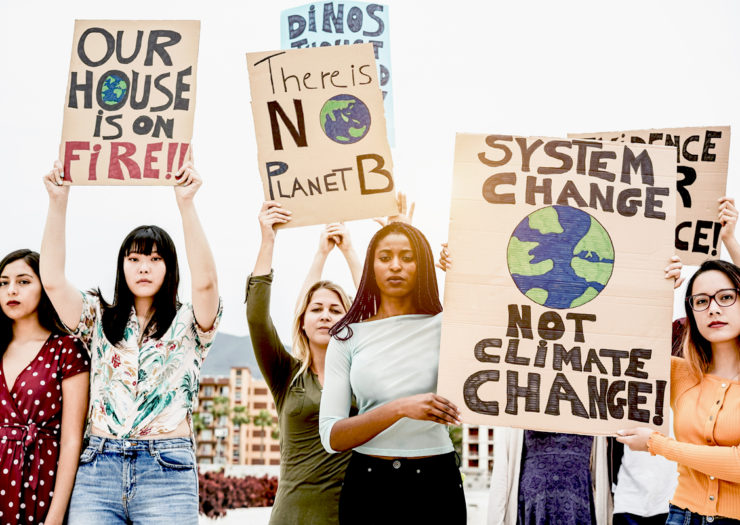 [Photo: Group of young women of different races hold up signs about climate change.]
