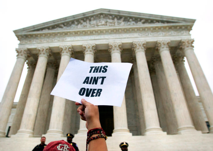 [Photo: Demonstrators hold signs in protest at the steps of the US Supreme Court.]