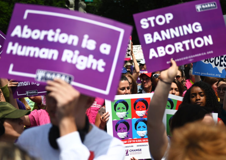 [Photo: Abortion rights supporters hold signs during a rally.]