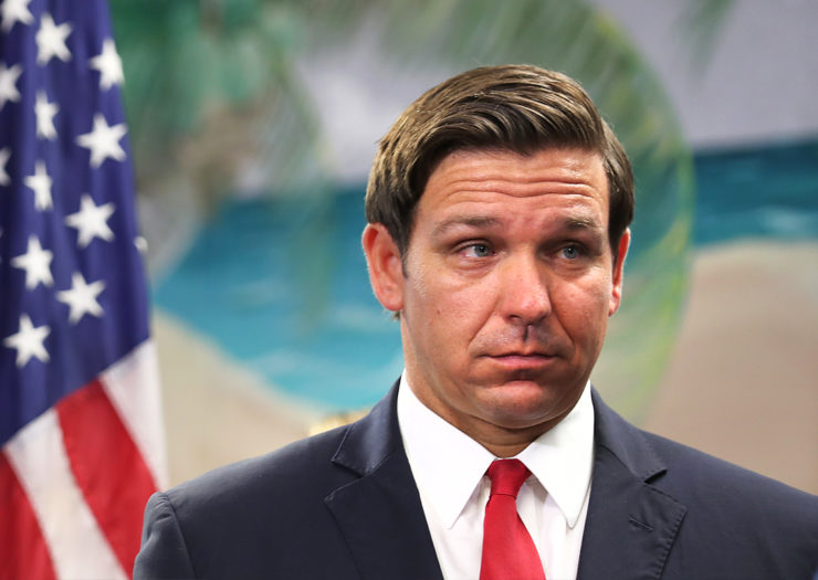 [Photo: Florida Governor Ron DiSantis looks on during a press conference.]