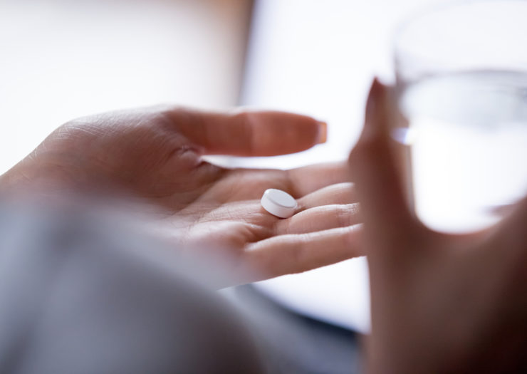 [Photo: A hand holding a pill.]