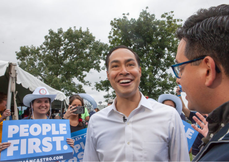 [Photo: Julián Castro in front of sign that says People First.]