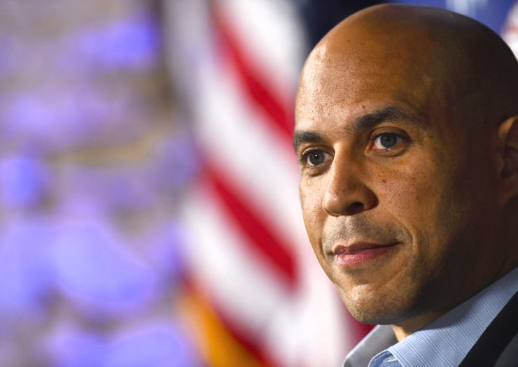 [Photo: U.S. Sen. Cory Booker looks on during an interview.]