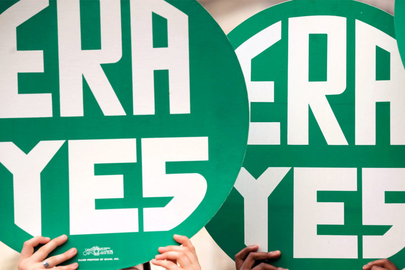[Photo: Two people holding signs that read 'ERA Yes' outside the U.S. Capitol.]