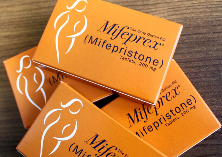 [Photo: Orange boxes of Mifeprex (mifepristone) lie on top of one another on a table.]