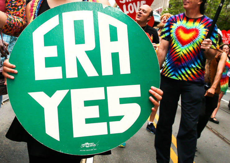 [Photo: Equal Rights Amendment (ERA) supporters hold signs as they march in a rally.]