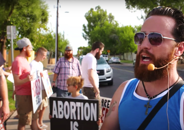 [Photo: A group of anti-abortion protesters gather outside an abortion clinic.]