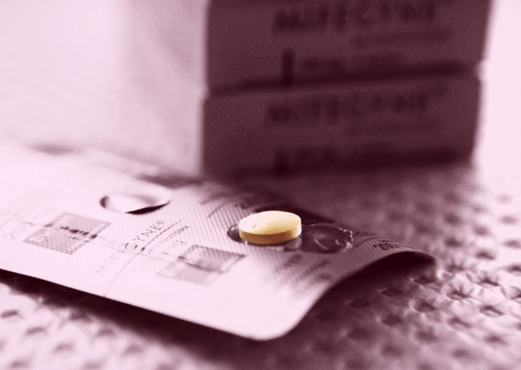 [Photo: A pill lays on top of a mifepristone blister pack.]