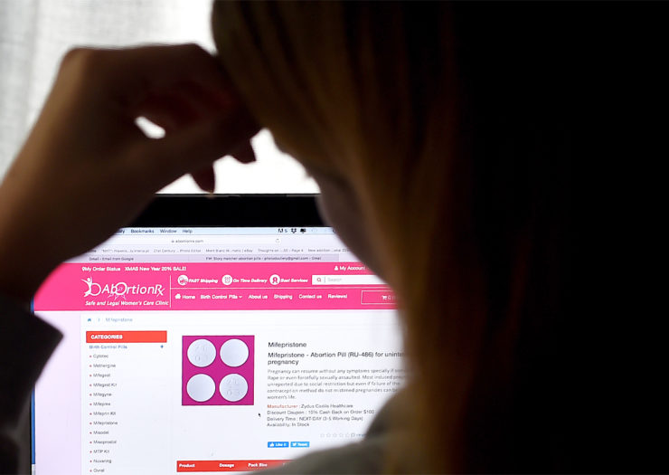 [Photo: A person looks at a website that sells pills for medication abortions.]