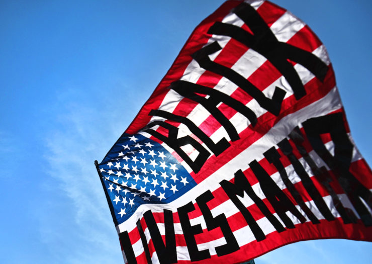 [Photo: An American flag with 'Black Lives Matter' superimposed on it waves in the wind.]