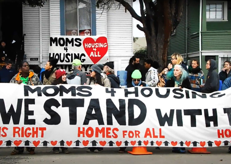 [Photo: A group of Moms 4 Housing supporters hold a large banner that reads 'Moms 4 Housing. We Stand With Them.']