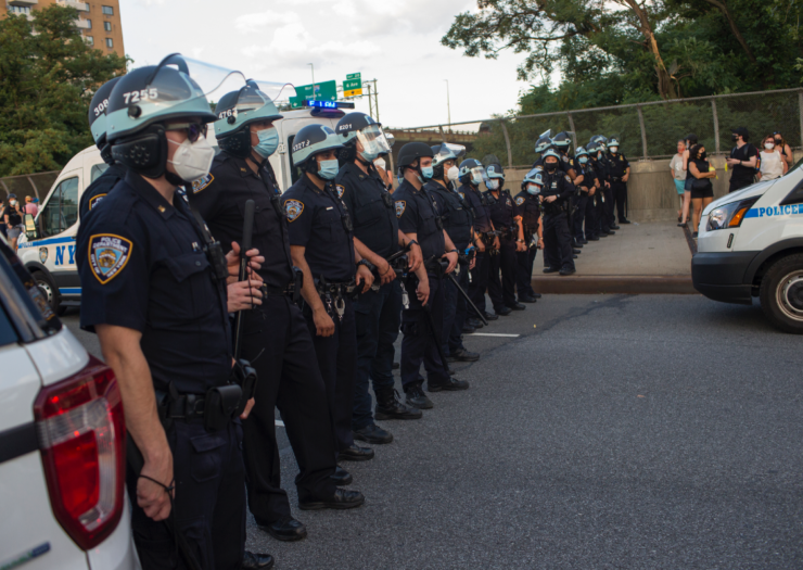 [Police officers in riot gear line up and block a road in New York]