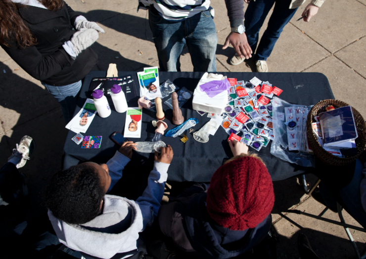 [Photo: Volunteers separate condoms to give away during a free HIV testing event]