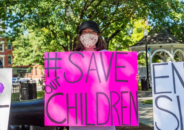 [PHOTO: A demonstrator with the QAnon hashtag #SaveOurChildren]