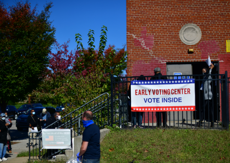 [PHOTO: People going into a building with a sign that reads early voting center]