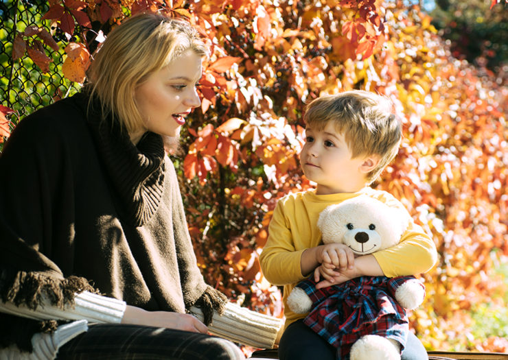 [Photo: A white mother and her young son have a conversation on a park bench during fall.]