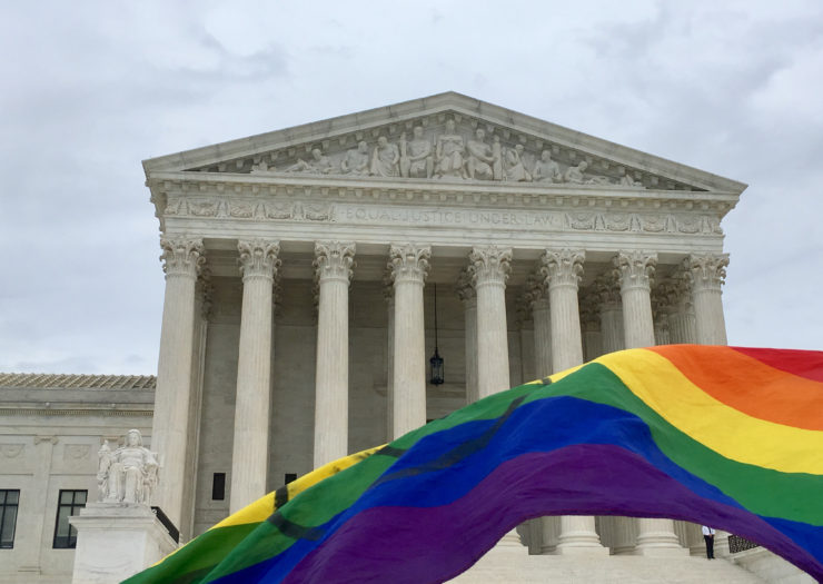[Photo: Rainbow flag draped flying in front of U.S. Supreme Court.]