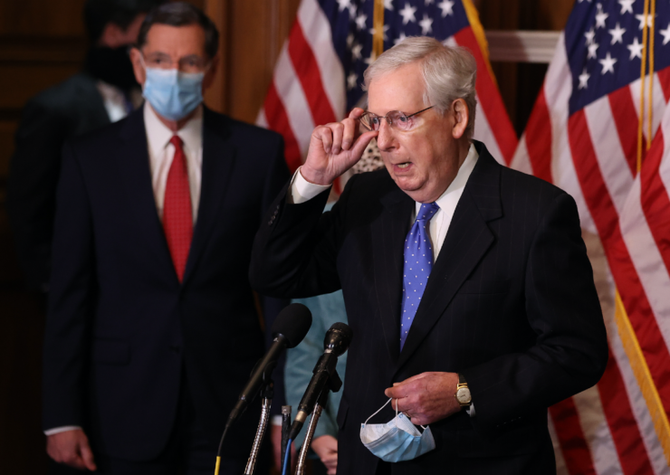 [PHOTO: Mitch McConnell adjusts his glasses while holding a mask with the other hand]