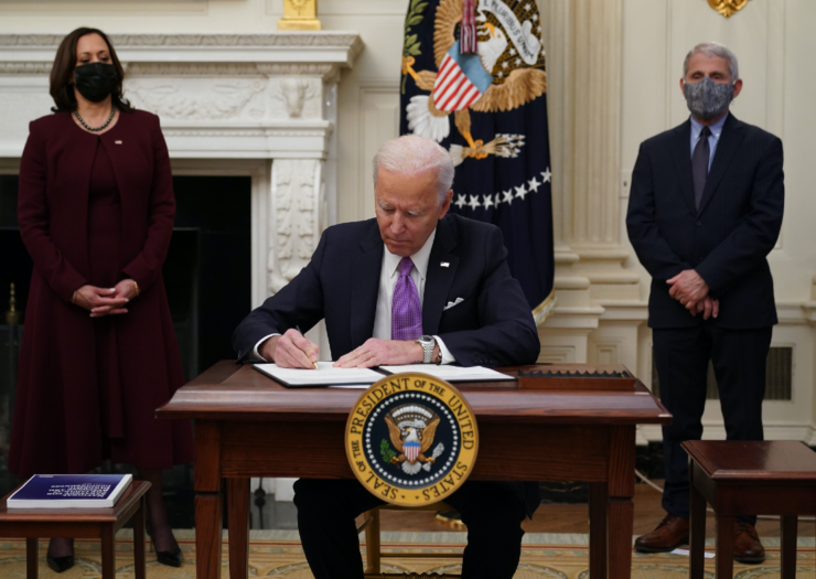 [PHOTO: Joe Biden sits signing a paper, Kamala Harris to the left, Anthony Fauci on the right]