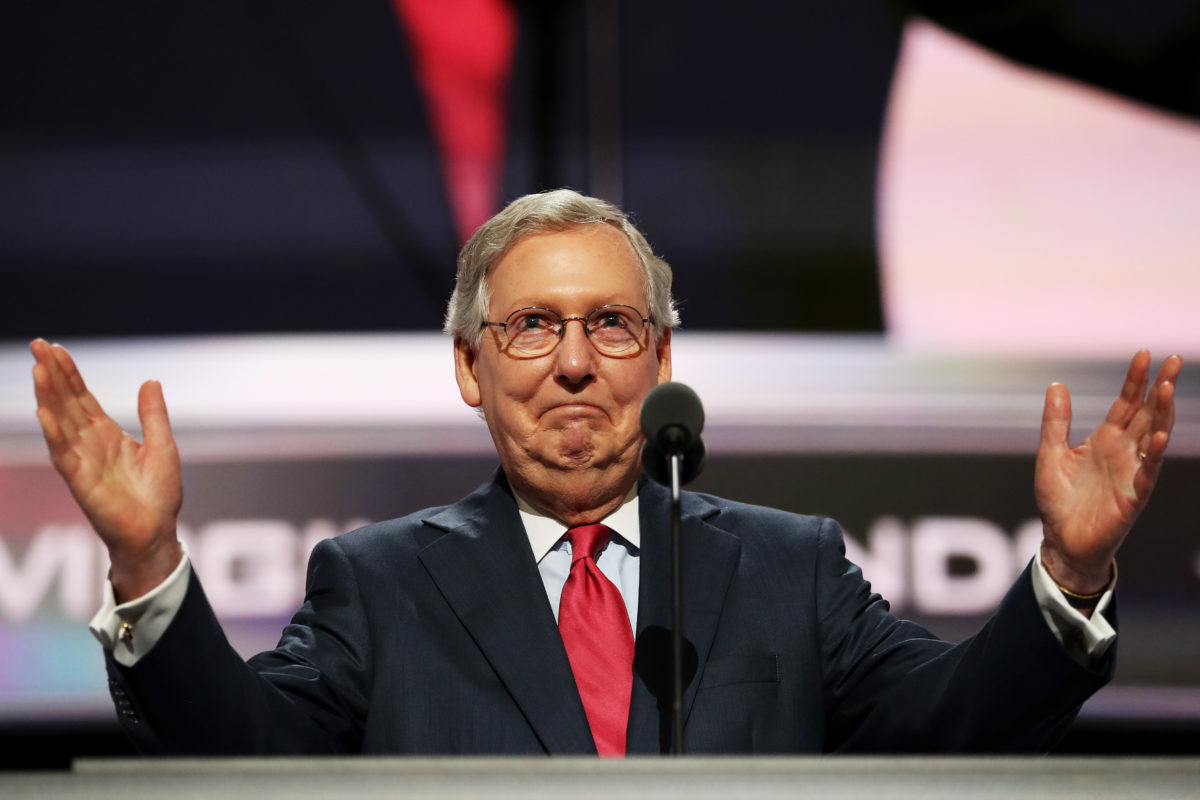 [PHOTO: Mitch McConnell standing at the podium with his hands out]