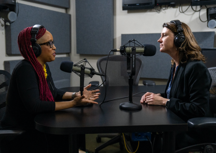 [PHOTO: Imani Gandy and Jessica Mason Pieklo both wear headphones sitting at a desk in front of a microphone]