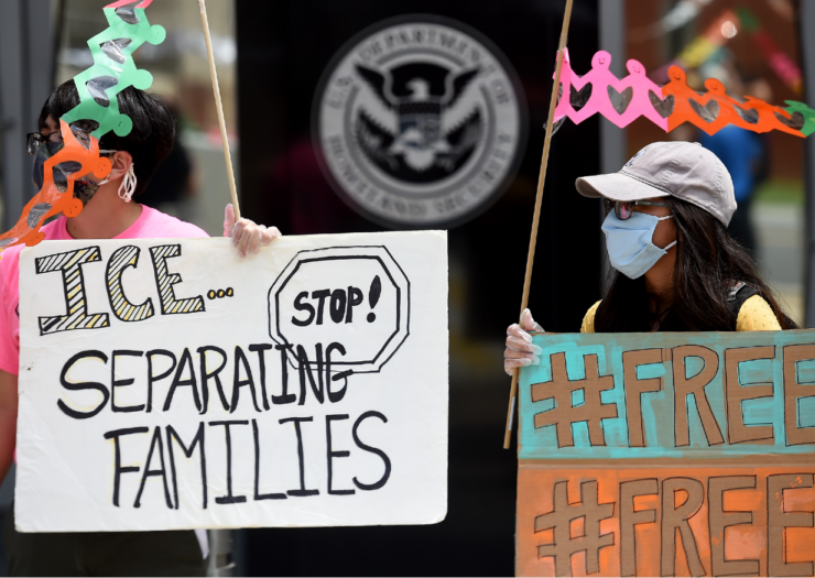 [PHOTO: Two women hold signs protesting ICE]