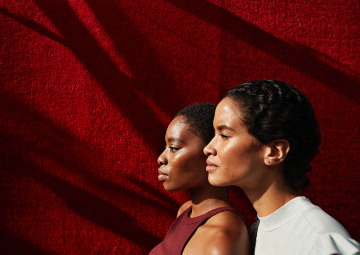 [PHOTO: Side profile of two black women, one standing behind the other]