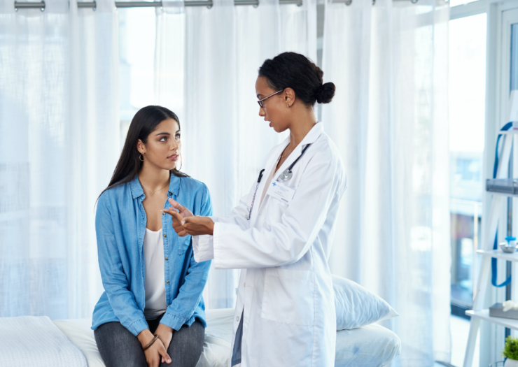 [PHOTO: Woman sitting and talking to her doctor]