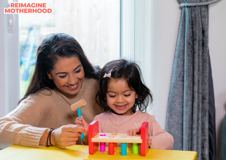 [PHOTO: A parent watching her child play with toys]